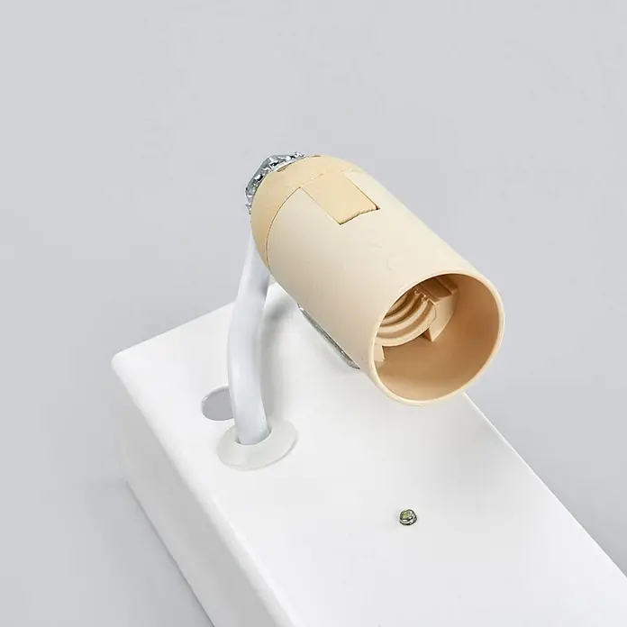 Lindby Wandleuchte Jasin - L x B x H: 10 x 30 x 7,5 cm, messing / gold, E14 - Beige Glühlampenfassung (E27) auf weißem, rechteckigem Leuchtenfuß mit gebogenem Arm.