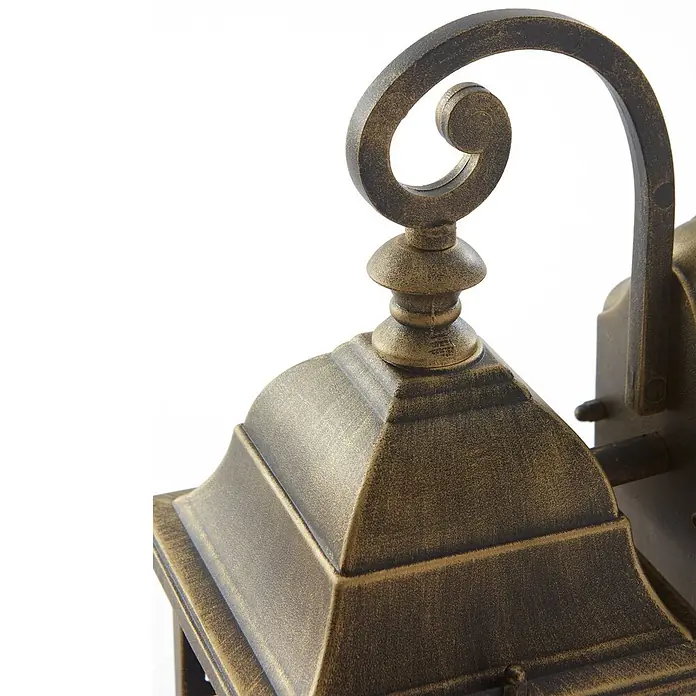 Lindby Wandleuchte Purnima - L x B x H: 17,8 x 15,1 x 31,8 cm, bronze / altmessing, bronze / altmessing, E27 - Nahaufnahme einer antiken bronzefarbenen Außenwandlaterne mit dekorativem Schnörkelarm und facettiertem Dach.