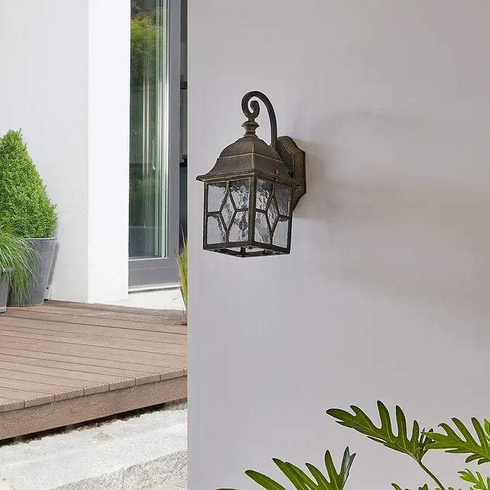 Lindby Wandleuchte Purnima - L x B x H: 17,8 x 15,1 x 31,8 cm, bronze / altmessing, bronze / altmessing, E27 - Wandlaterne aus Antikmessing mit gemustertem Glas, neben moderner Glastür.