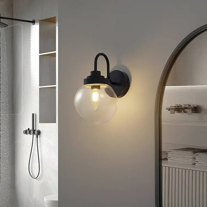 Lucande Wandleuchte Badolo - L x B x H: 21,5 x 15 x 25 cm, schwarz, klar / transparent, E14 - Schwarze Wandleuchte mit klarer Glaskugel beleuchtet einen modernen Badezimmerbereich neben einer Dusche.