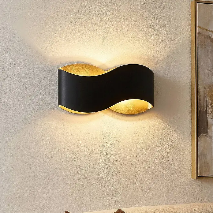 Lindby Wandleuchte Dailin - L x B x H: 10 x 30 x 15 cm, schwarz, G9 - Schwarze, goldene Wellen-Wandleuchte, die warmes Licht nach oben und unten auf eine texturierte Wand wirft.