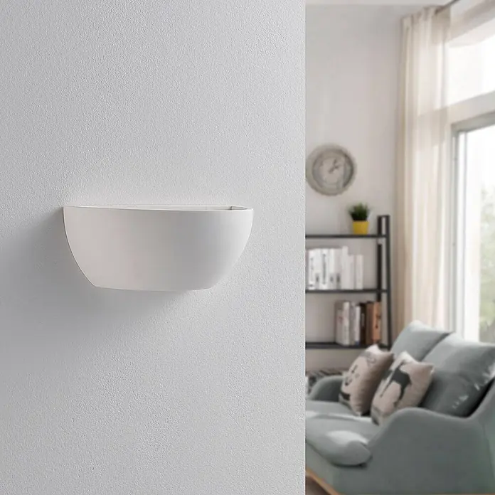 Lindby Wandleuchte Jimmy - L x B x H: 12 x 24,5 x 9,5 cm, weiß / opal, E14 - Weiße, schalenförmige Wandleuchte an einer Wand in einem Wohnzimmer, die indirektes Licht spendet.
