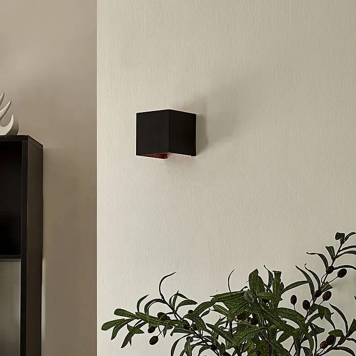 Arcchio Wandleuchte Zuzana - L x B x H: 9,7 x 9,7 x 9,7 cm, schwarz, G9 - Schwarze, würfelförmige Wandleuchte mit kupferfarbener Innenseite, an einer Wand montiert.