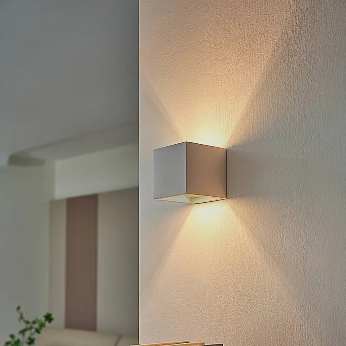 Lindby Wandleuchte Freja - weiß / opal, G9 - Quadratische graue Wandleuchte auf einer strukturierten Wand, wirft warmes Licht nach oben und unten.
