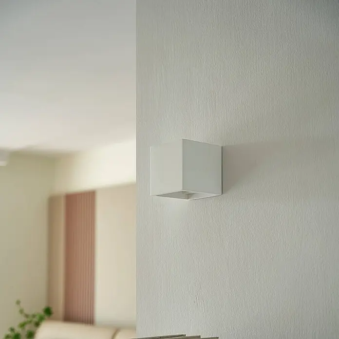 Lindby Wandleuchte Freja - weiß / opal, G9 - Weiße quadratische Wandleuchte an einer strukturierten Wand montiert.
