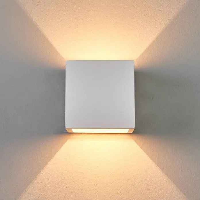 Lindby Wandleuchte Freja - weiß / opal, G9 - Weiße quadratische Wandleuchte, die eine strukturierte Wand mit warmem Licht nach oben und unten beleuchtet.