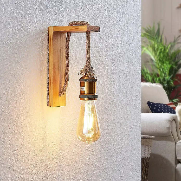 Lindby Wandleuchte Helou - Holz hell, E27 - Wandleuchte aus Holz mit geflochtener Kordel, messingfarbener Fassung und Vintage-LED-Birne, beleuchtet eine strukturierte Wand im Wohnzimmer.