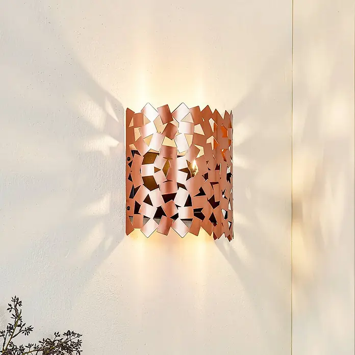 Lucande Wandleuchte Aeloria - kupfer, E27 - Kupferfarbene Wandleuchte mit geometrischem Aussparungsmuster, die Licht und Schatten an die Wand wirft.