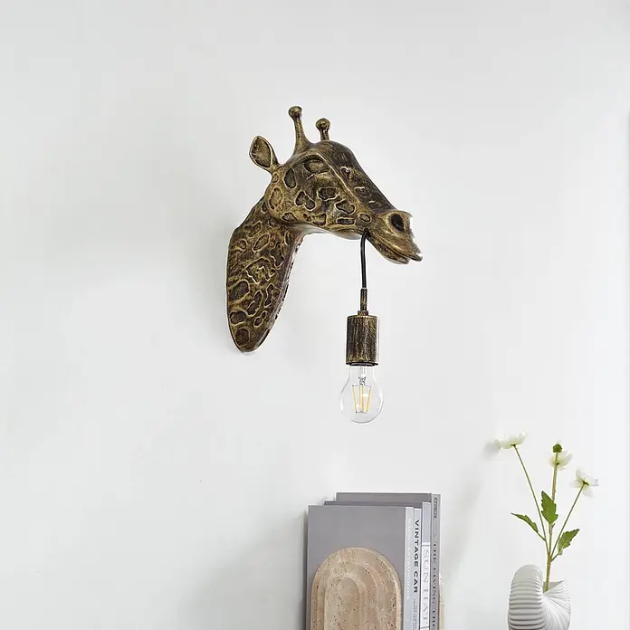 Lindby Wandleuchte Nirvathia - bronze / altmessing, E27 - Goldene Giraffenkopf-Wandlampe mit strukturierter Oberfläche und einer freiliegenden Glühbirne, die aus dem Maul hängt.