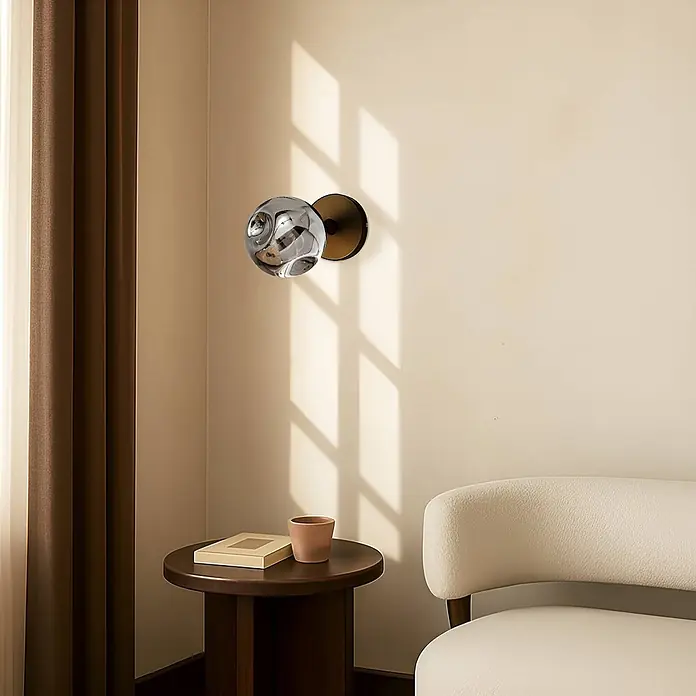 Lindby Wandleuchte Valentina - schwarz, alu / grau / zink, G9 - Moderne kugelförmige Wandleuchte mit strukturierter silberner Metallschirm und dunklem Sockel, an der Wand in einem modernen Raum montiert.