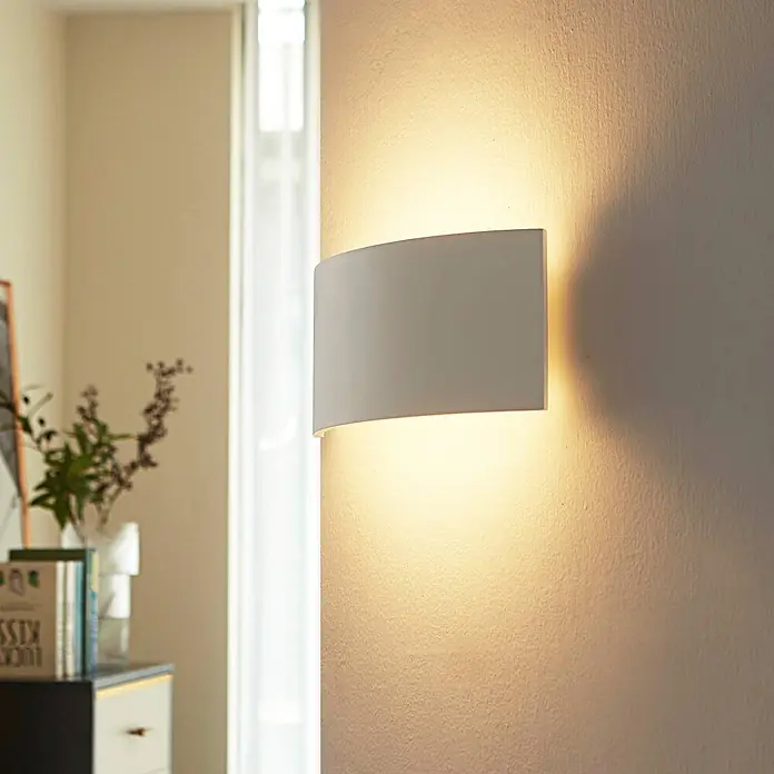 Lindby Wandleuchte Naike - L x B x H: 8 x 35 x 15 cm, weiß / opal, weiß / opal, G9 - Weißes, gebogenes Wandlicht spendet warmes Auf- und Ablicht an einer texturierten Wand in gemütlichem Raumambiente.