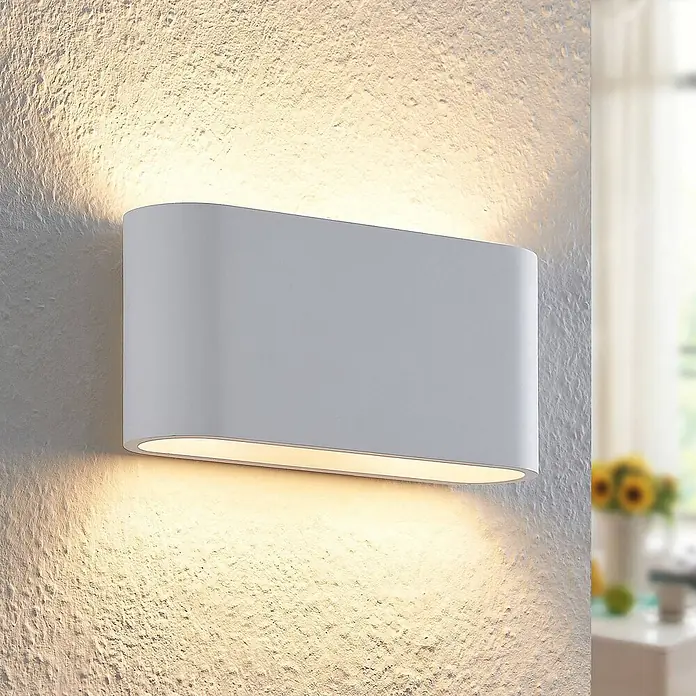Lindby Wandleuchte Mavora - L x B x H: 7 x 25 x 12 cm, weiß / opal, G9 - Weiße, rechteckige LED-Wandleuchte mit abgerundeten Kanten, an einer strukturierten Wand, wirft warmes Licht nach oben und unten.