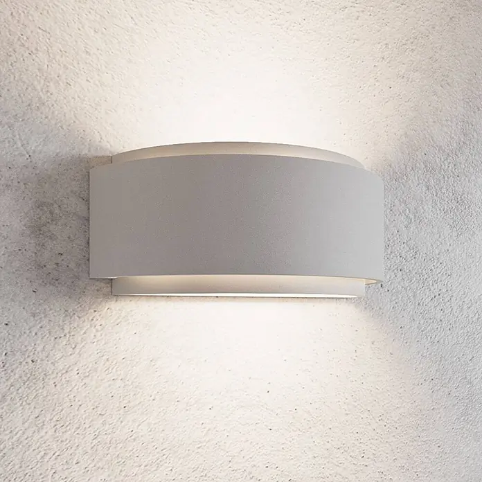 Lindby Wandleuchte Cassian - L x B x H: 12 x 32 x 13 cm, weiß / opal, E14 - Hellgraue, geschwungene Wandleuchte beleuchtet eine strukturierte Wand mit indirektem Licht nach oben und unten.