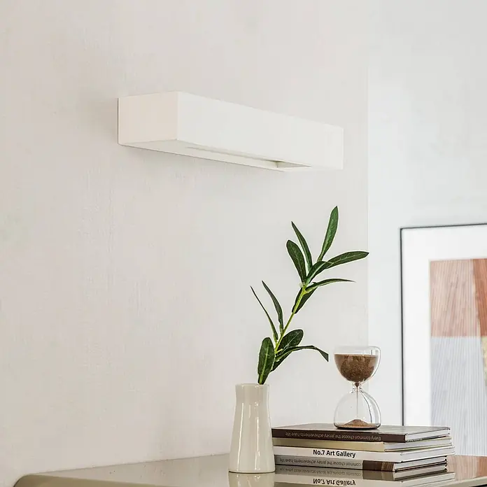 Lindby Wandleuchte Matteo - L x B x H: 9,5 x 36 x 6 cm, weiß / opal, E14 - Weiße, rechteckige Wandleuchte an einer strukturierten Wand in einem modernen Interieur.