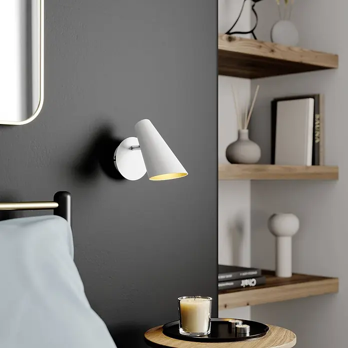 Lucande Wandleuchte Wibke - L x B x H: 17 x 9 x 24 cm, weiß / opal, weiß / opal, GU10 - Weiße konische Wandlampe mit warmem Licht, an einer dunklen Wand im Schlafzimmer montiert.