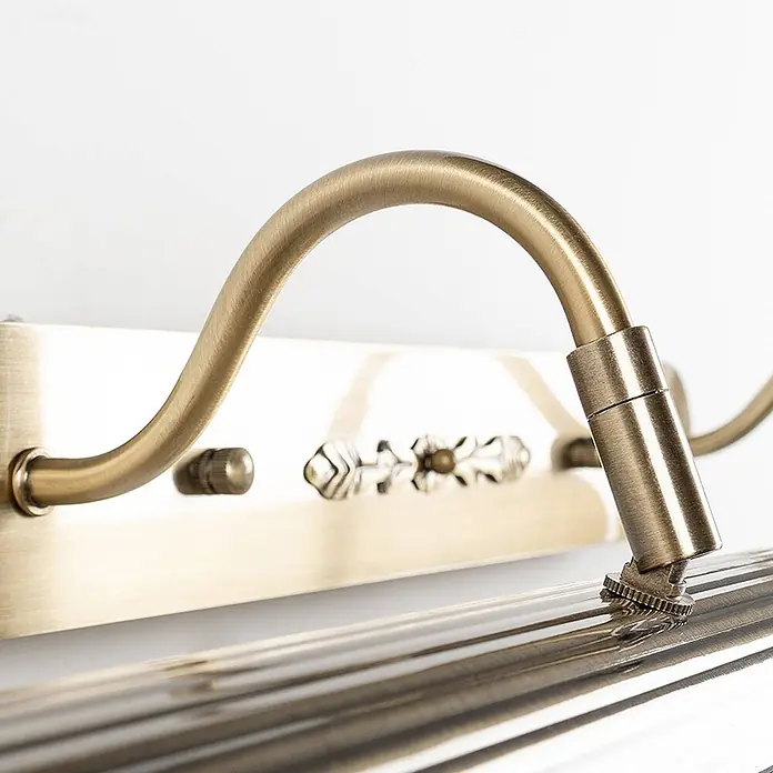 Lindby Wandleuchte Joely - bronze / altmessing, bronze / altmessing, E14 - Nahaufnahme einer messingfarbenen Wandleuchte mit gebogenem Arm, verstellbarem Kopf und geripptem Glasschirm.