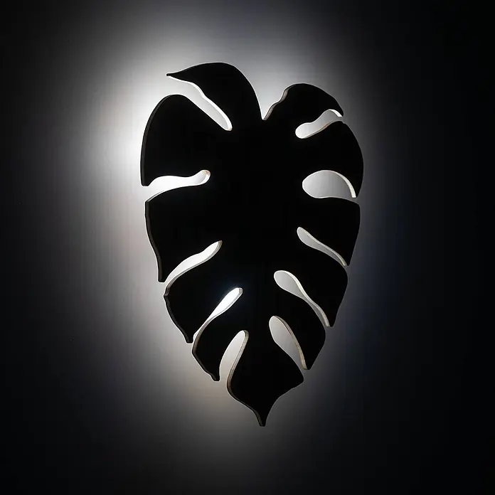 Envostar Wandleuchte Folah - L x B x H: 5 x 35 x 40 cm, Holz hell, Holz hell, G9 - Dunkle Monstera-Blatt Wandleuchte, die eine leuchtende Silhouette an eine dunkle Wand wirft.