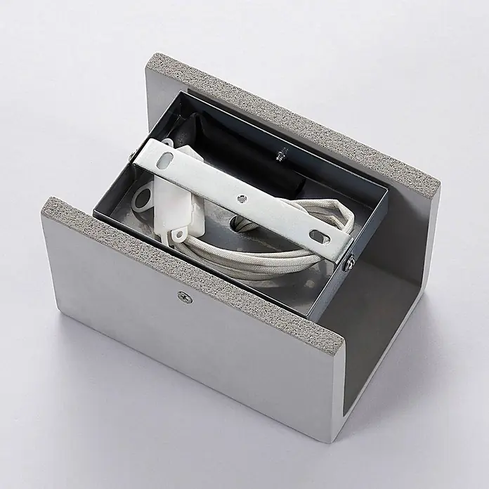 Lindby Wandleuchte Gerda - alu / grau / zink, GU10 - Silberfarbenes Wandleuchtengehäuse mit interner Halterung, weißem Stecker und aufgerolltem Kabel.