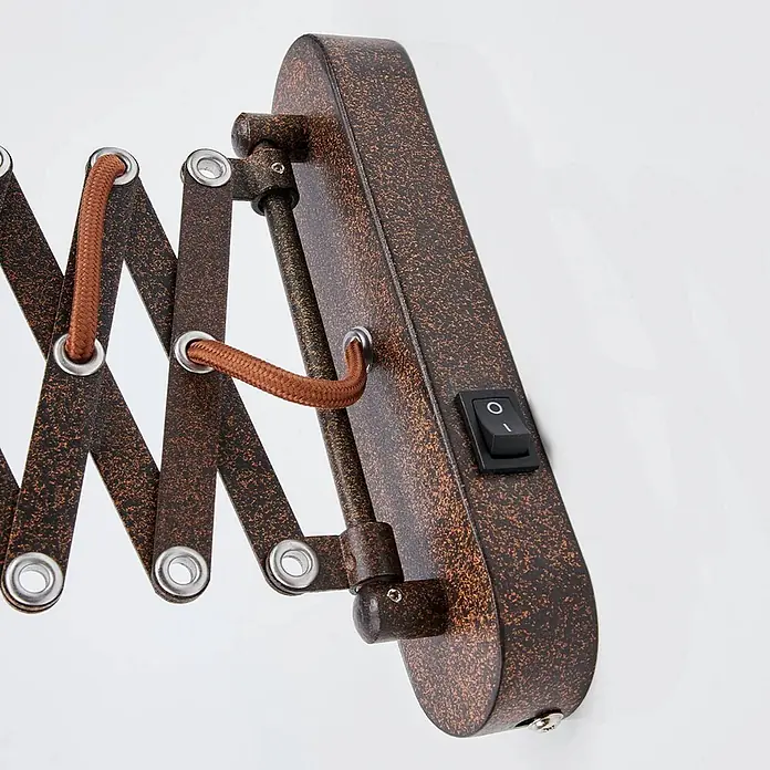 Lindby Wandleuchte Curtis - L x B x H: 57 x 13 x 23 cm, braun / rost, braun / rost, E14 - Nahaufnahme einer Wandlampenbasis in antikem Bronze-Finish mit Akkordeonarm, brauner Flechtschnur und schwarzem Kippschalter.
