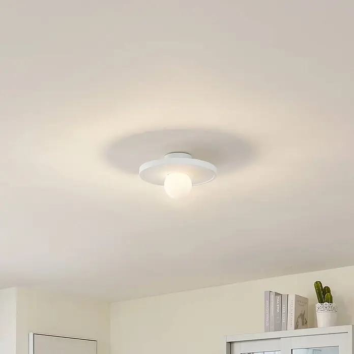 Lindby Wandleuchte Nielson - L x B x H: 28 x 28 x 15,5 cm, weiß / opal, E27 - Eine moderne weiße Deckenleuchte mit Kugel-Diffusor beleuchtet einen hellen Raum.