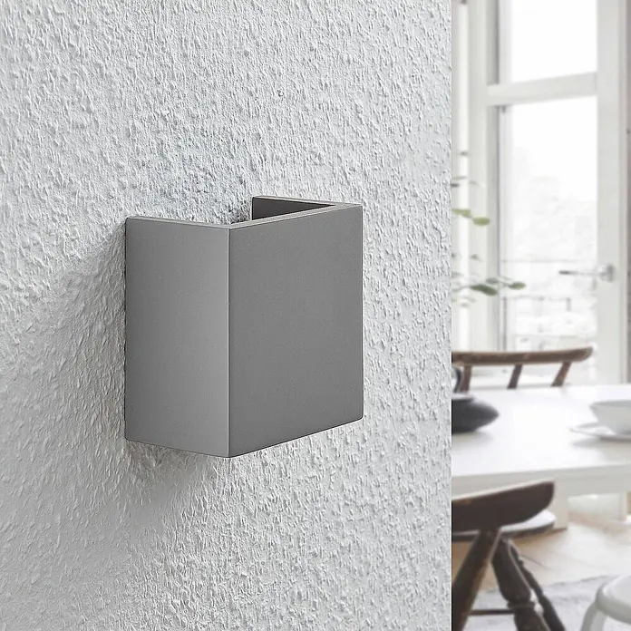 Lindby Wandleuchte Smira - L x B x H: 7,5 x 12,5 x 12,5 cm, alu / grau / zink, G9 - Graue U-förmige Wandleuchte an einer strukturierten weißen Wand, die eine Raumbeleuchtung bietet.