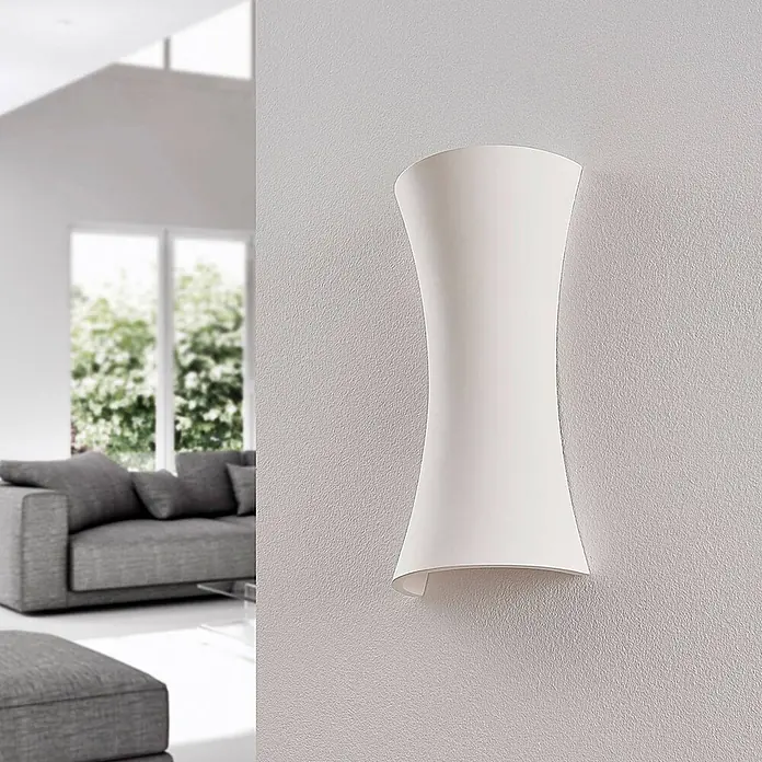 Lindby Wandleuchte Edon - L x B x H: 7,5 x 15 x 30 cm, weiß / opal, E14 - Weiße sanduhrförmige Wandleuchte an einer strukturierten Wand in einem modernen Wohnzimmer.