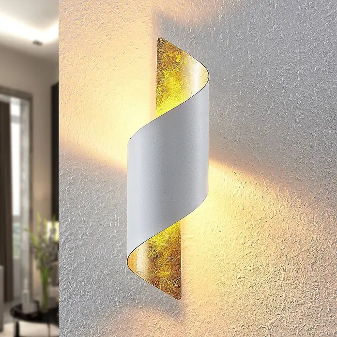 Lindby Wandleuchte Desirio - weiß / opal, weiß / opal, E14 - Weiße und goldene Spiral-Wandleuchte, die warmes Licht nach oben und unten auf eine strukturierte Wand wirft.