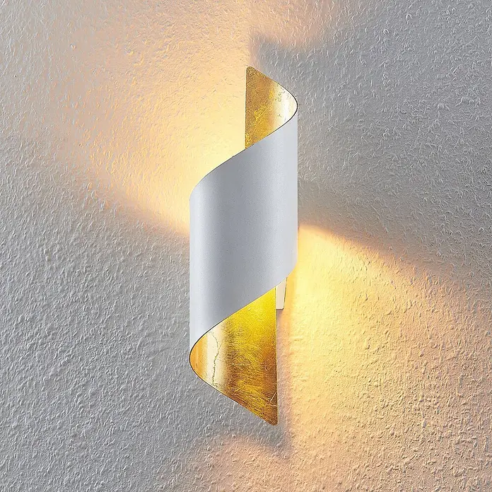 Lindby Wandleuchte Desirio - weiß / opal, weiß / opal, E14 - Weiße Spiral-Wandleuchte mit Goldblatt-Innenseite, die eine strukturierte Wand warm beleuchtet.