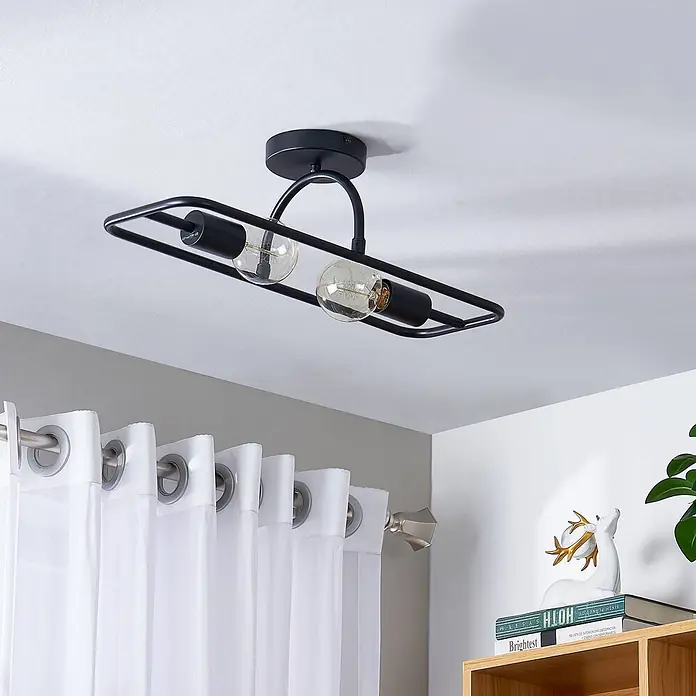 Lucande Wandleuchte Tornike - schwarz, E27 - Schwarze, rechteckige Deckenleuchte aus Metall mit zwei sichtbaren Filamentlampen, an der Decke über weißen Vorhängen und Regal.