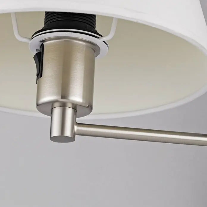 Lindby Wandleuchte Pola - alu / grau / zink, E27 - Lampenfassung aus gebürstetem Metall mit schwarzem Schalter, an einem Metallarm befestigt, unter einem weißen Stofflampenschirm.