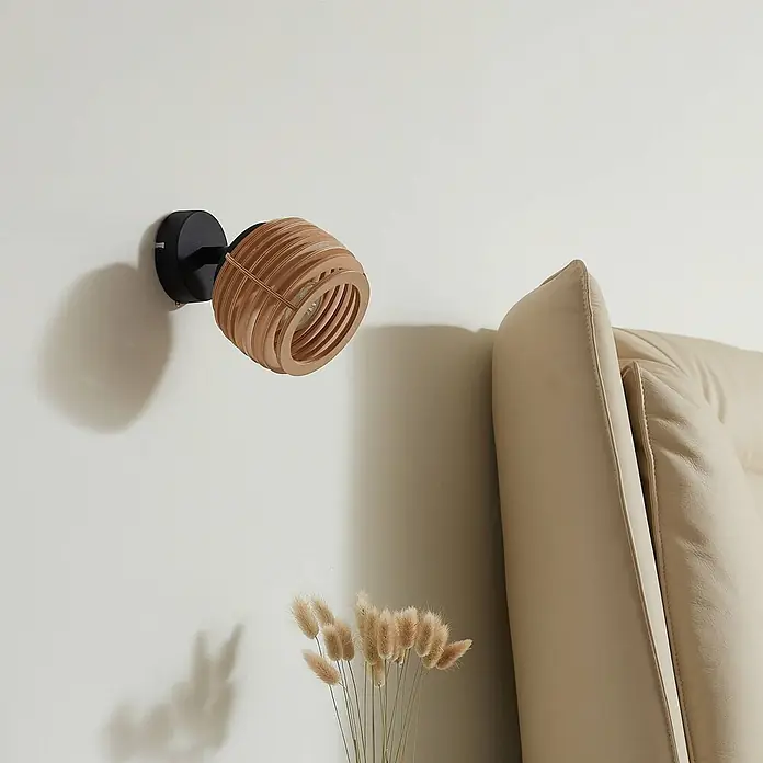 Lindby Wandleuchte Ediz - L x B x H: 17,3 x 12,7 x 12,7 cm, schwarz, Holz hell, GU10 - Wandleuchte mit hellem Holzlamellenschirm und schwarzem Sockel, über Trockenblumen und neben einem hellen Sessel montiert.