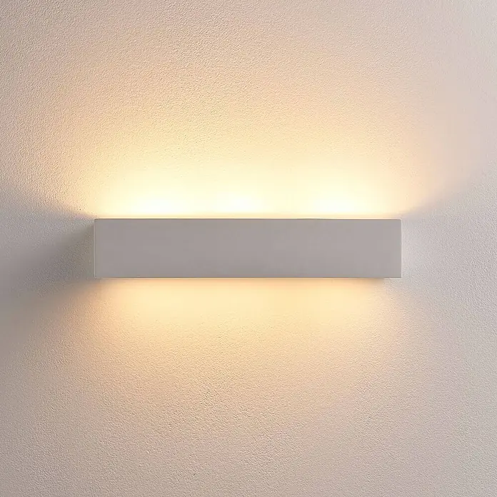 Lindby Wandleuchte Arya - weiß / opal, G9 - Rechteckige hellgraue/weiße Wandleuchte, die die strukturierte Wand nach oben und unten mit warmem Licht beleuchtet.