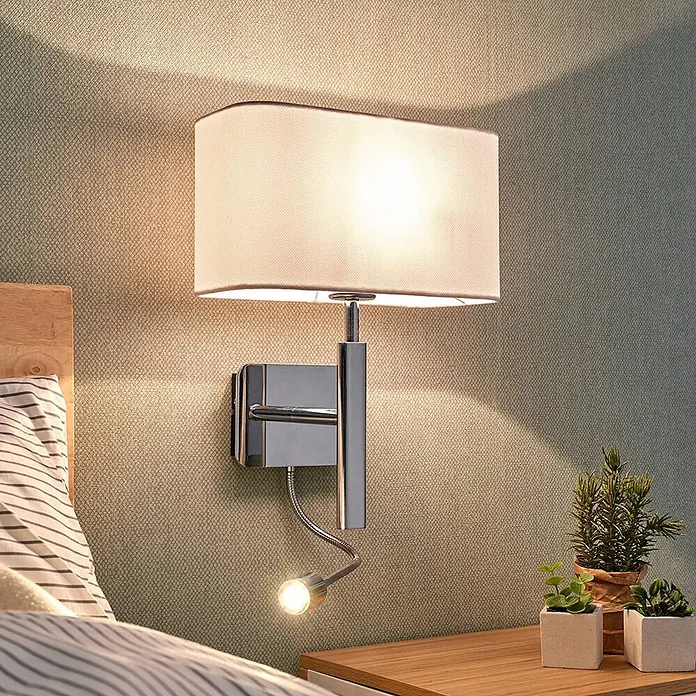 Lucande Wandleuchte Jettka - L x B x H: 18 x 28 x 63 cm, chrom / silber, E27 - Verchromte Wandleuchte mit rechteckigem Stoffschirm und verstellbarem LED-Lesespot, über einem Nachttisch montiert.