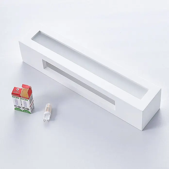 Lindby Wandleuchte Arya - weiß / opal, G9 - Weiße rechteckige LED-Leuchte mit Schlitzen, daneben zwei verpackte und eine unverpackte G9 LED-Birne.