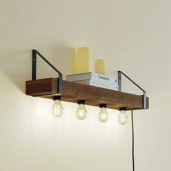 Lindby Wandleuchte Vatana - Holz dunkel, E27 - Wandregal aus Holz mit schwarzen Metallhalterungen und vier sichtbaren Glühbirnen unten. Zwei Bücher und zwei Kerzen stehen auf dem Regal.