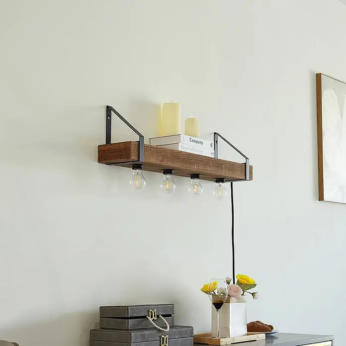 Lindby Wandleuchte Vatana - Holz dunkel, E27 - Rustikales Wandregal aus dunklem Holz mit schwarzen Metallhalterungen und vier Glühbirnen, mit Kerzen und Büchern über einem Schrank.