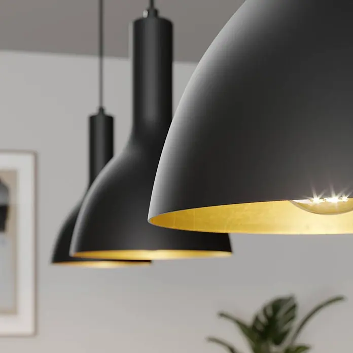 Arcchio Pendelleuchte Cosmina - L x B x H: 100 x 17,5 x 26 cm, schwarz, Schwarz, gold, E27 - Drei schwarze Pendelleuchten mit goldfarbener Innenseite beleuchten einen Raum. Die vordere Lampe strahlt hell.