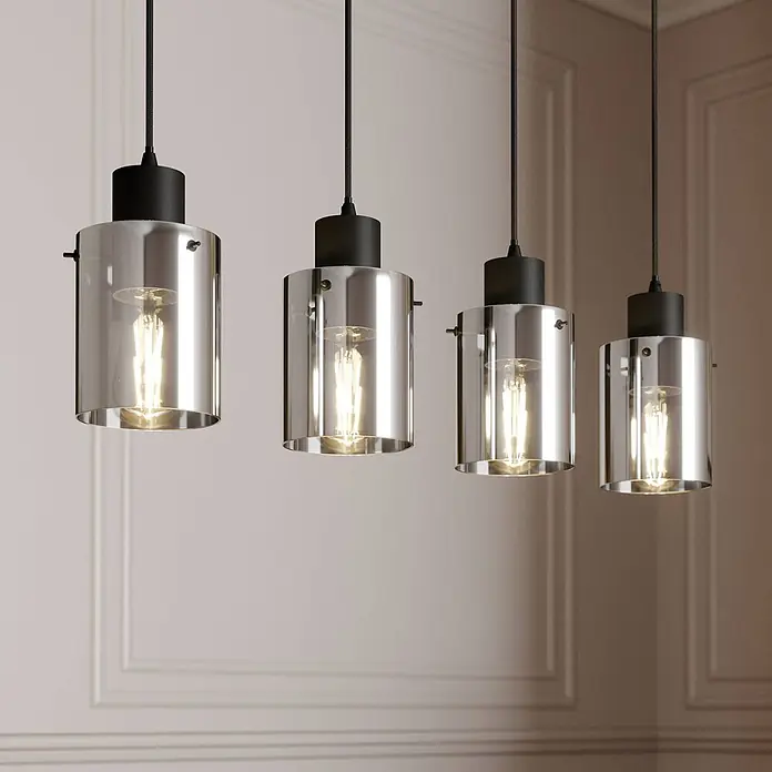 Lindby Pendelleuchte Kourtney - L x B x H: 75 x 12 x 18 cm, alu / grau / zink, Schwarz, rauchgrau, E27 - Vier Pendelleuchten mit Rauchglas-Schirmen und schwarzer Hardware beleuchten einen Raum mit getäfelten Wänden.
