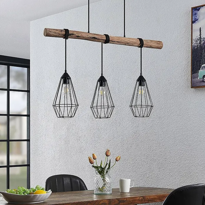 Lindby Pendelleuchte Eldarion - schwarz, Schwarz matt, holz hell, E27 - Dreiflammige Industrie-Pendelleuchte mit Holzbalken und schwarzen geometrischen Käfigen über einem Esstisch.