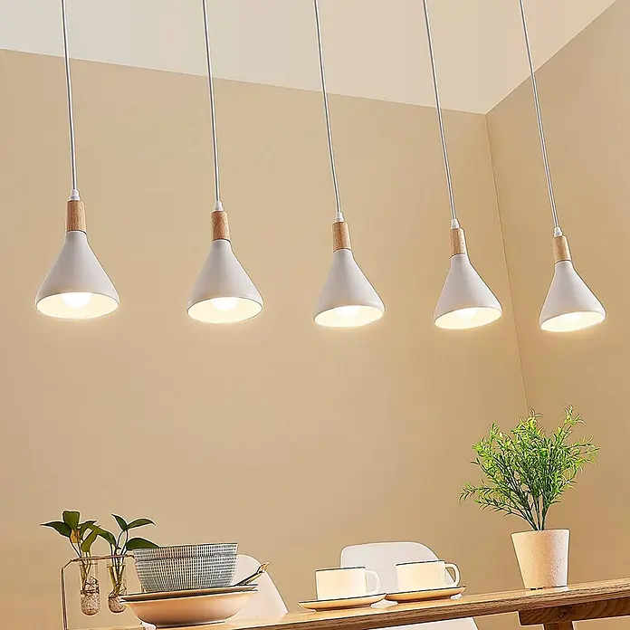 Lindby Pendelleuchte Arina - weiß / opal, weiß, holz hell, E14 - Fünf weiße, konische Pendelleuchten mit Holzdetails hängen über einem Esstisch.