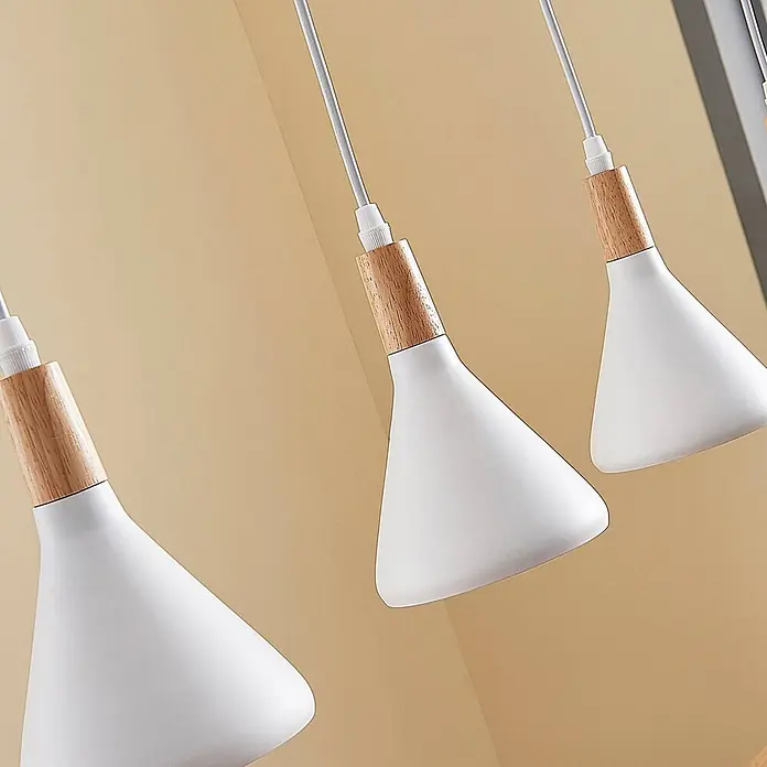 Lindby Pendelleuchte Arina - weiß / opal, weiß, holz hell, E14 - Drei weiße konische Pendelleuchten mit Holzakzenten hängen vor einem warmen beigen Hintergrund.