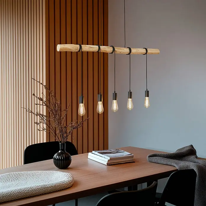 Lindby Pendelleuchte Rom - L x B x H: 116 x 7,5 x 150 cm, schwarz, Schwarz matt, holz hell, E27 - Eine Pendelleuchte mit fünf Edison-Birnen hängt von einem Holzstrahl über einem Esstisch.