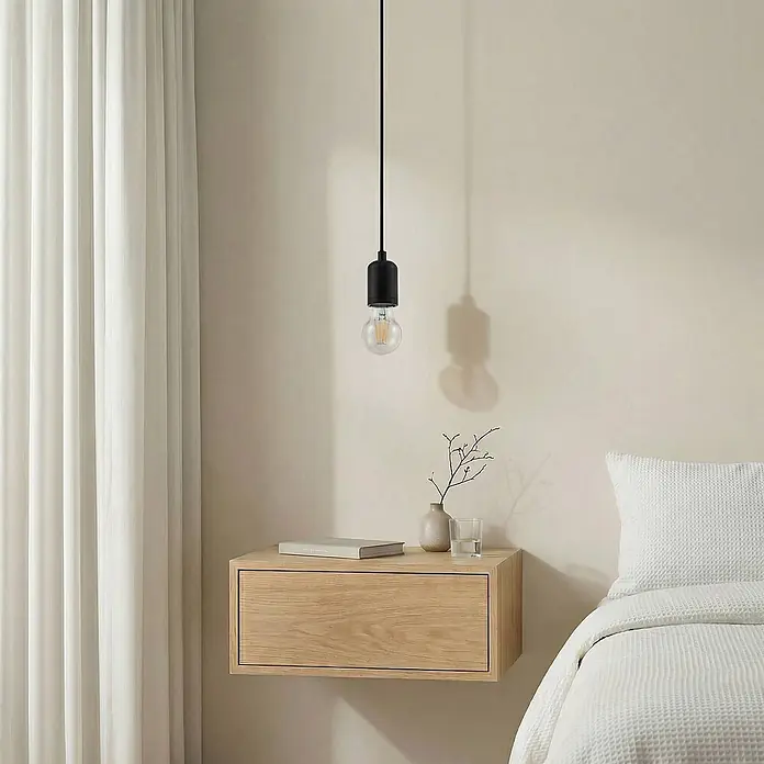 Lindby Pendelleuchte Hattie - L x B x H: 4,7 x 4,7 x 7 cm, schwarz, Schwarz, E27 - Minimalistische schwarze Pendelleuchte mit klarer Birne, über einem hölzernen Nachttisch hängend.