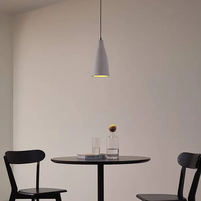 Lindby Pendelleuchte Sanne - alu / grau / zink, betongrau, E27 - Graue konische Pendelleuchte beleuchtet einen modernen Essbereich über einem schwarzen Tisch.