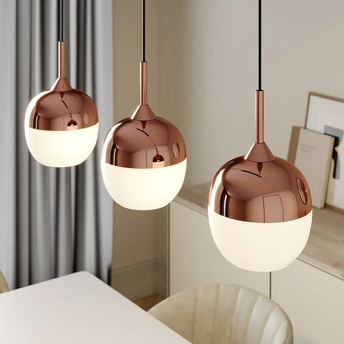 Lindby Pendelleuchte Rangina - kupfer, Kupfer, weiß, E27 - Drei moderne Pendelleuchten mit Kupferoberteilen und weißen Glaskugeln hängen über einem Esstisch.