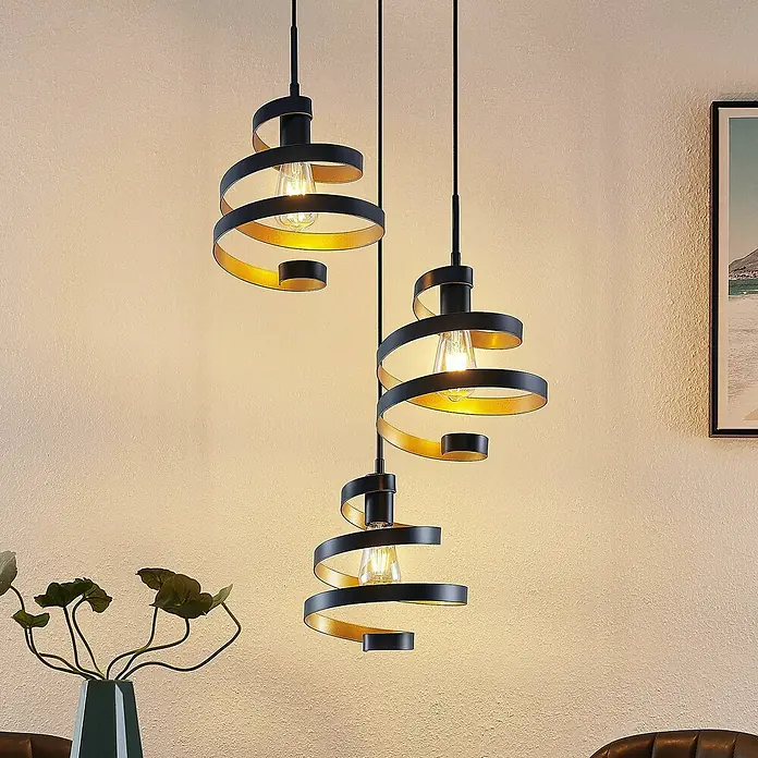Lindby Pendelleuchte Colten - schwarz, mattSchwarz, gold, E27 - Drei schwarz-goldene Spiral-Pendelleuchten hängen beleuchtet in einem Raum.
