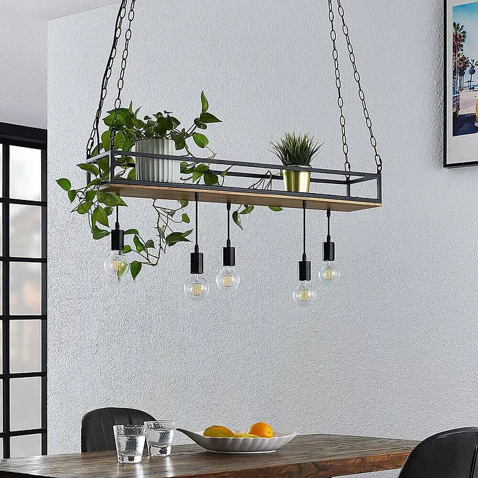 Lindby Pendelleuchte Kirista - L x B x H: 100 x 20 x 15 cm, Schwarz, kiefer dunkel, E27 - Industrielle Hängelampe mit schwarzem Metallrahmen, Holzablage, Pflanzen und fünf Glühbirnen, über einem Esstisch hängend.