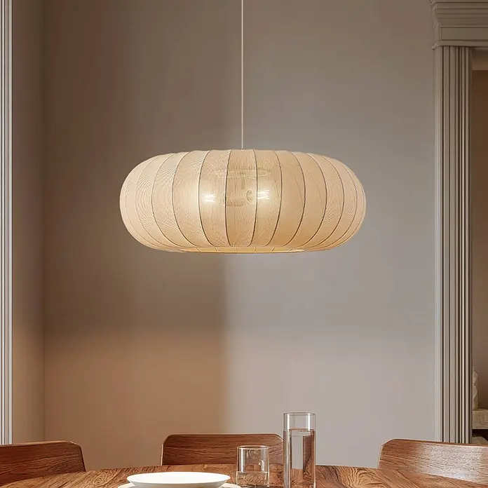Lindby Pendelleuchte Helin - L x B x H: 70 x 70 x 26 cm, creme / amber, beige, E27 - Große ovale Hängeleuchte mit hellem Holz- oder Naturfaserschirm, beleuchtet über einem Holztisch hängend.