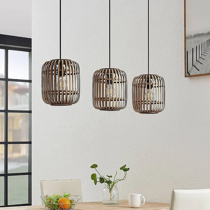 Lindby Pendelleuchte Canyana - L x B x H: 105 x 21,5 x 25 cm, Holz hell, natur, E27 - Drei Pendelleuchten mit Bambusgeflecht hängen über einem Esstisch und zeigen ihr natürliches Design.