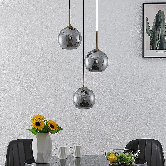 Lindby Pendelleuchte Jurian - L x B x H: 32 x 32 x 17,5 cm, alu / grau / zink, bronze, rauchgrau, E27 - Drei Pendelleuchten aus Rauchglas mit Messingakzenten, die einen modernen Essbereich beleuchten.
